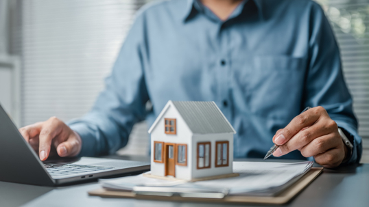 Man signing documents with tiny home on top | Gill & Kadochnikov P.C.